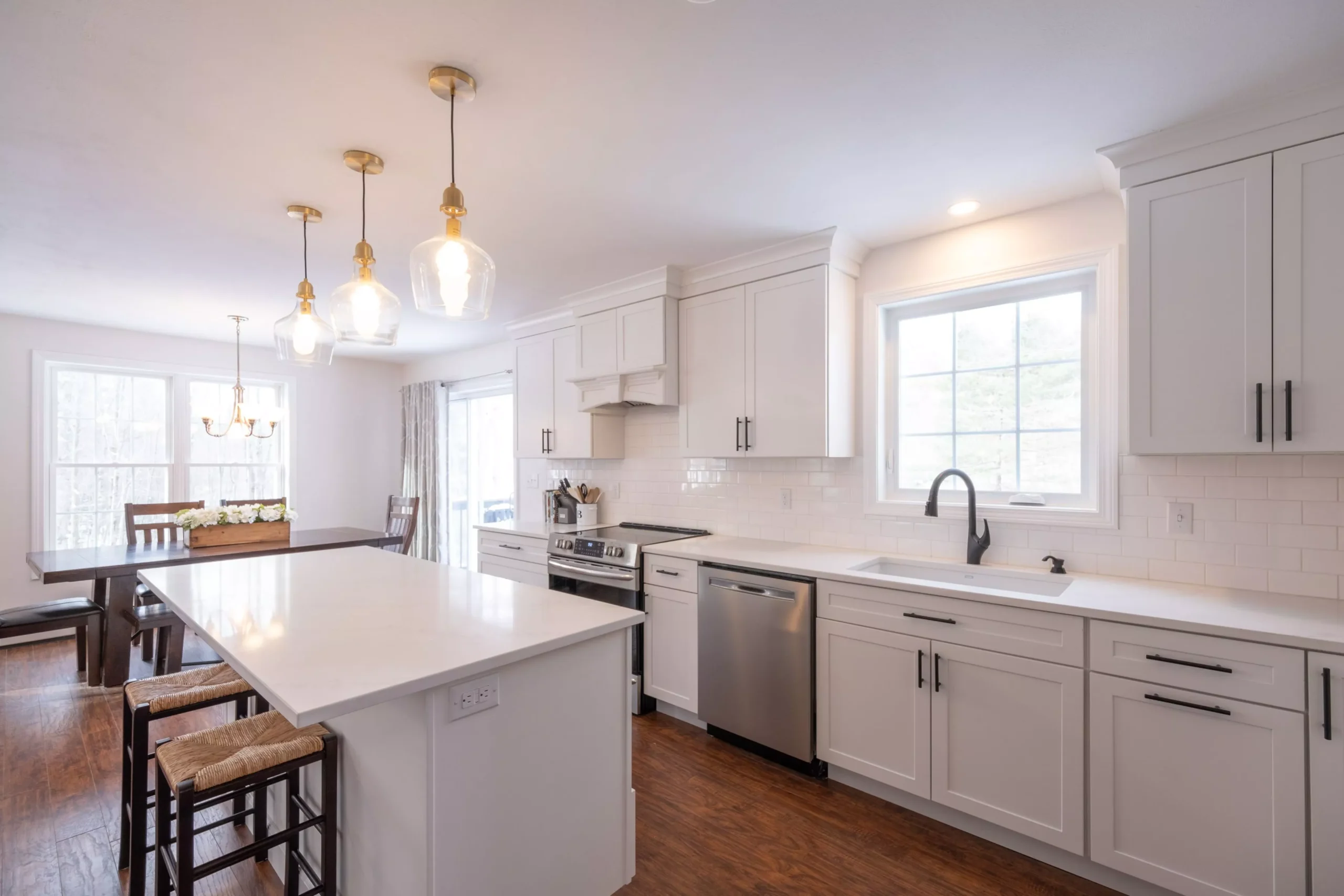 Bright, modern kitchen with white shaker cabinets, quartz countertops, stainless steel appliances, dark wood floor, and go... Bright, modern kitchen with white shaker cabinets, quartz countertops, stainless steel appliances, dark wood floor, and go...